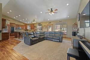Living room with recessed lighting, light wood finished floors, a ceiling fan, and lofted ceiling