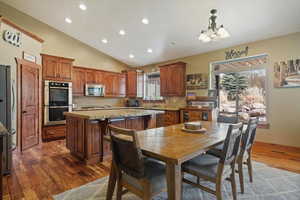 Dining room featuring wood floors, vaulted ceiling, and a chandelier