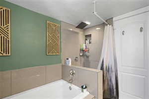 Bathroom with a shower stall, a bath, and a textured ceiling