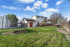 Back of property featuring a trampoline, a patio, a shed, and a fenced backyard