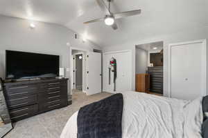 Bedroom with multiple closets, a textured ceiling, light colored carpet, and a ceiling fan
