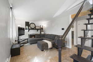 Living area featuring a stone fireplace and light tile patterned floors