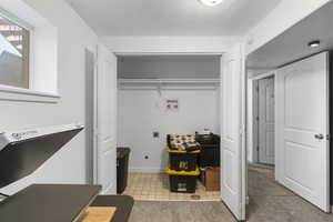 Laundry area featuring washer hookup, electric dryer hookup, light colored carpet, and light tile patterned floors