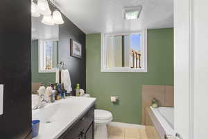 Full bathroom with a textured ceiling, a garden tub, vanity, and light tile patterned flooring