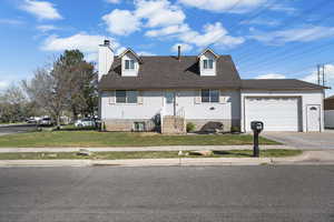 Cape cod house featuring an attached garage, a chimney, roof with shingles, concrete driveway, and a front lawn