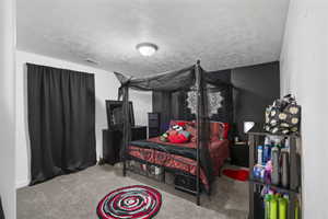 Bedroom featuring light colored carpet and a textured ceiling