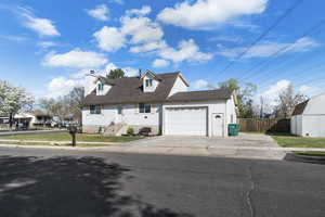 Cape cod-style house featuring a chimney, an attached garage, driveway, and roof with shingles