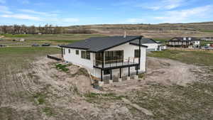 View of South side and back of home with shingled roof, and view of deck