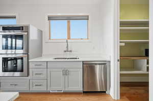 Kitchen with stainless steel appliances, quartz counters, light wood flooring, and healthy amount of natural light