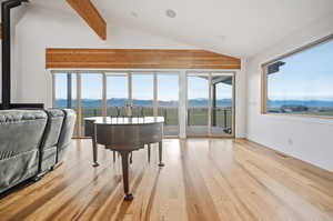 Living area featuring lofted ceiling with beams, a mountain view, light flooring, and healthy amount of natural light