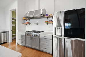 Kitchen featuring stainless steel appliances, light wood flooring, open shelves