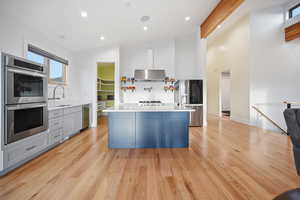 Kitchen with stainless steel appliances, lofted ceiling, recessed lighting, a center island, and light wood flooring