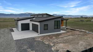 View of home's exterior featuring a mountain view, a view of countryside, concrete driveway, and an attached garage