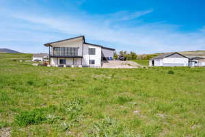 Back of house featuring a balcony, a mountain view, stucco siding, and a view of rural / pastoral area
