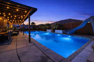 Swimming pool featuring a water slide, a patio area, and a fenced backyard