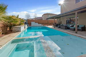 Combined pool / hot tub with a patio, an outdoor lounge area, and a fenced backyard
