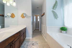 Bathroom with vanity, a garden tub, and light tile patterned floors