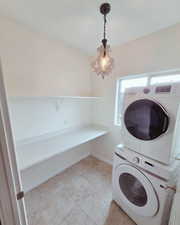 Laundry room featuring stacked washing machine and dryer and light tile patterned flooring