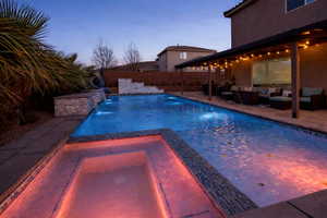 Pool at dusk with a fenced backyard, a patio area, a pool with connected hot tub, and an outdoor living space