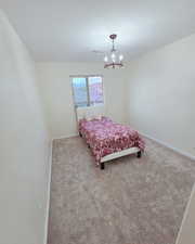 Bedroom with light carpet and hanging lights