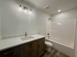 Bathroom featuring vanity, dark wood-type flooring, shower / washtub combination, and recessed lighting