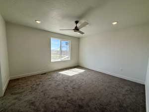 Unfurnished room with a textured ceiling, dark carpet, ceiling fan, and recessed lighting