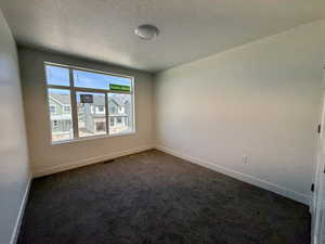 Unfurnished room featuring dark carpet and a textured ceiling