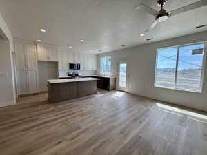 Kitchen featuring open floor plan, recessed lighting, light countertops, a kitchen island, and a textured ceiling