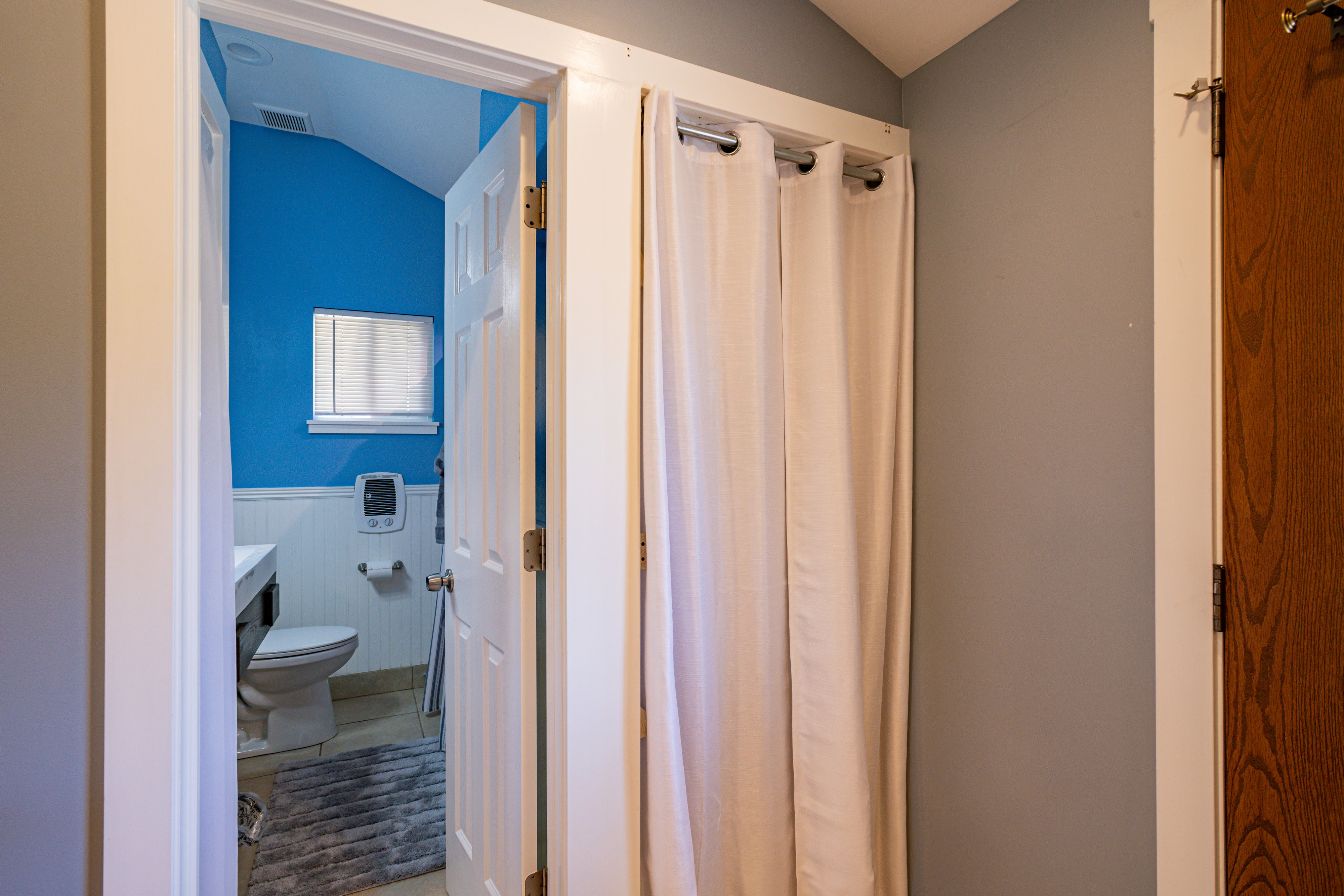 Corridor featuring vaulted ceiling, wainscoting, and light tile patterned floors