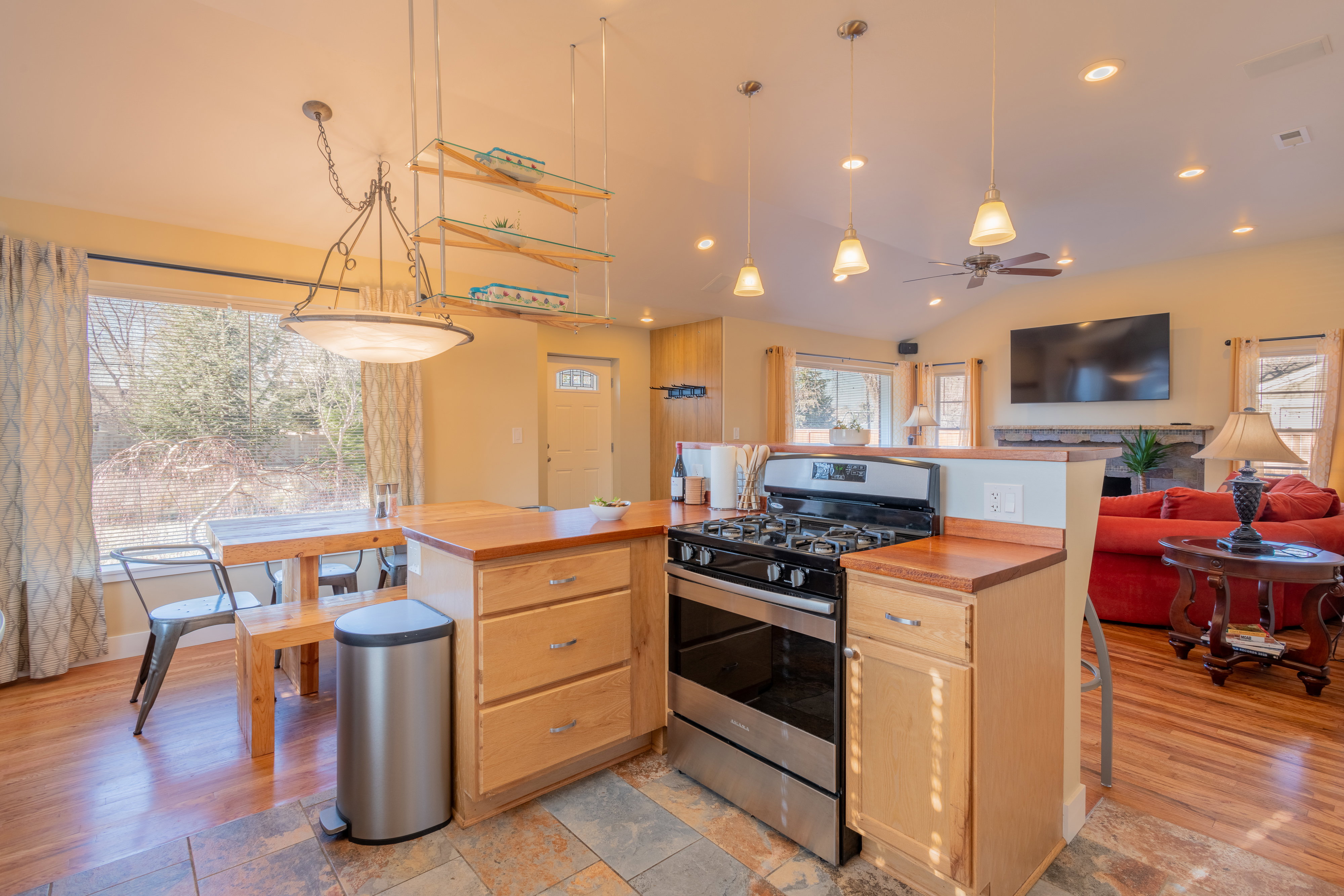 Kitchen featuring stainless steel gas range oven, light wood finish cabinets, open floor plan, a kitchen breakfast bar, and vaulted ceiling