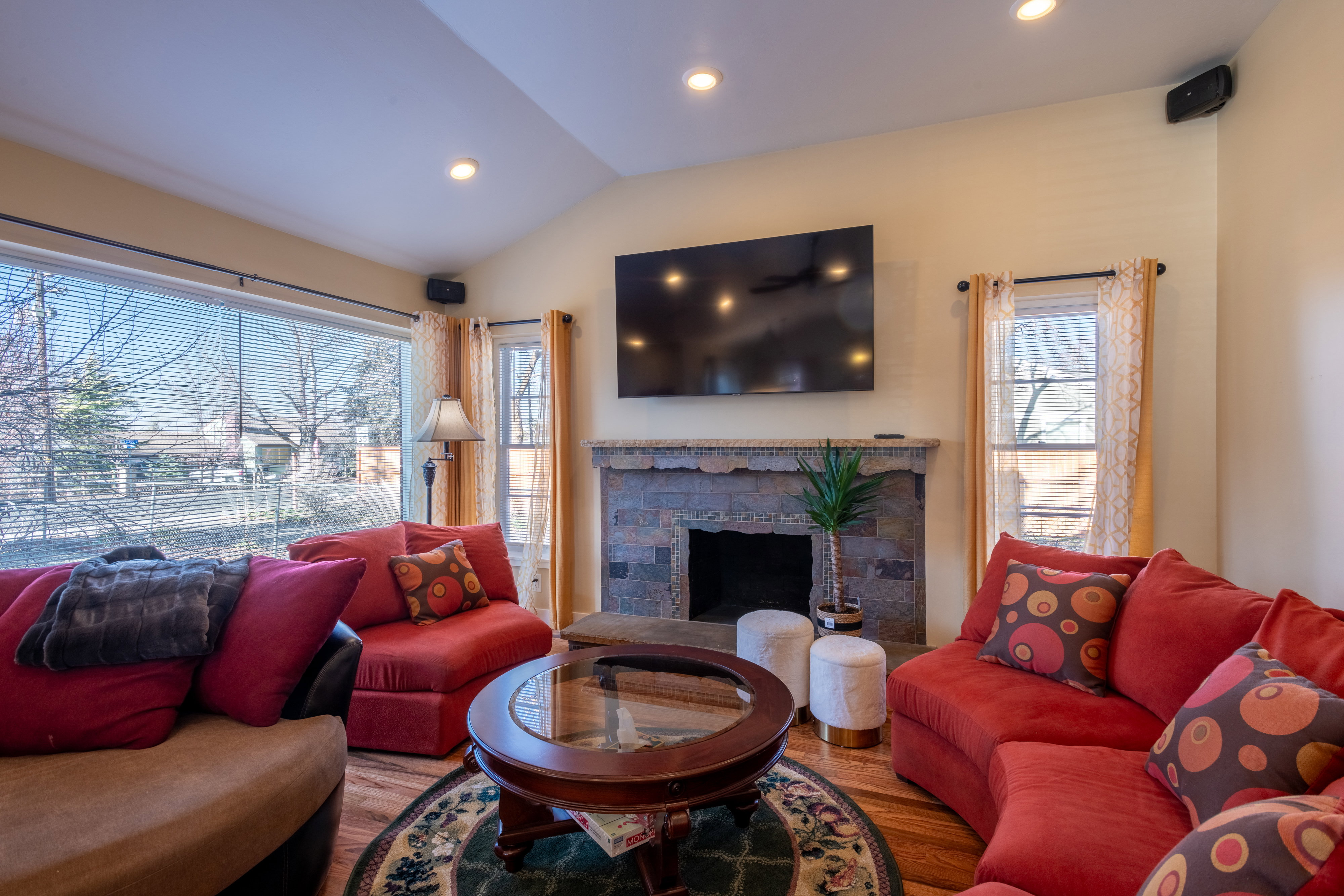 Living room with lofted ceiling, a fireplace, wood finished floors, and recessed lighting