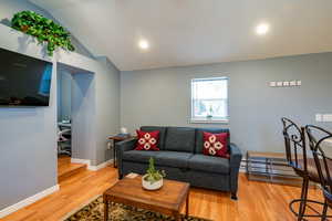 Living area featuring light wood-style floors, vaulted ceiling, a desk, and baseboard heating