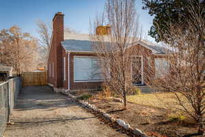 View of front of property featuring a shingled roof, a chimney, gravel driveway, and brick siding