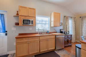 Kitchen featuring light wood finish cabinetry, stainless steel appliances, open shelves, wooden counters, and lofted ceiling