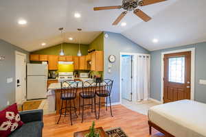 Kitchen featuring white appliances, a breakfast bar, light wood-style flooring, hanging light fixtures, and a peninsula