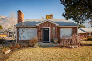 Single story home featuring brick siding, a chimney, and a mountain view