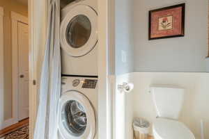 Laundry room with stacked washing machine and dryer and wainscoting