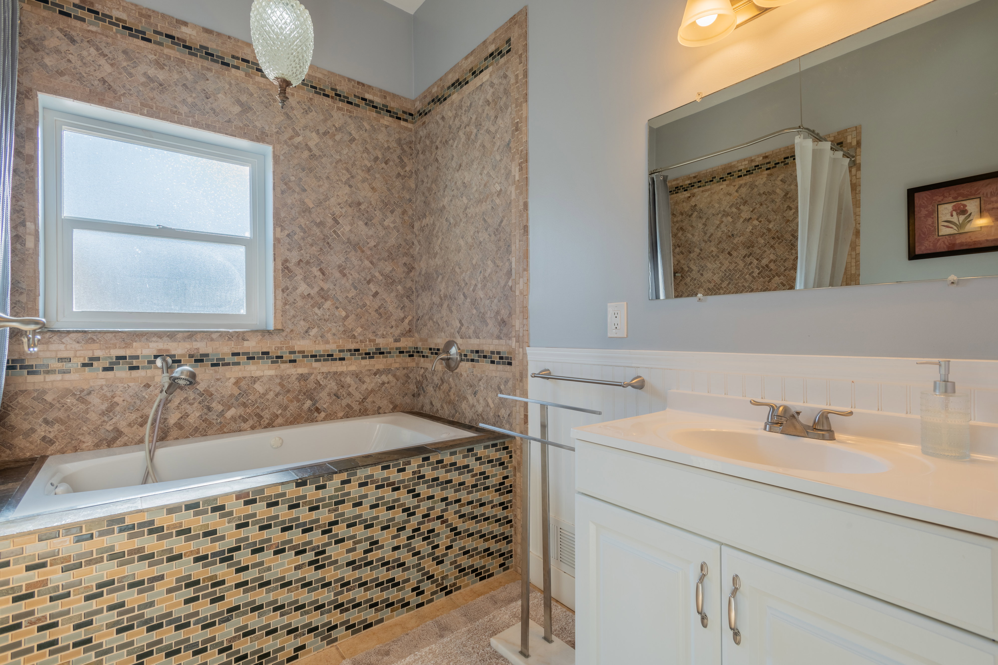 Full bathroom with vanity, a garden tub, a wainscoted wall, and a shower with curtain