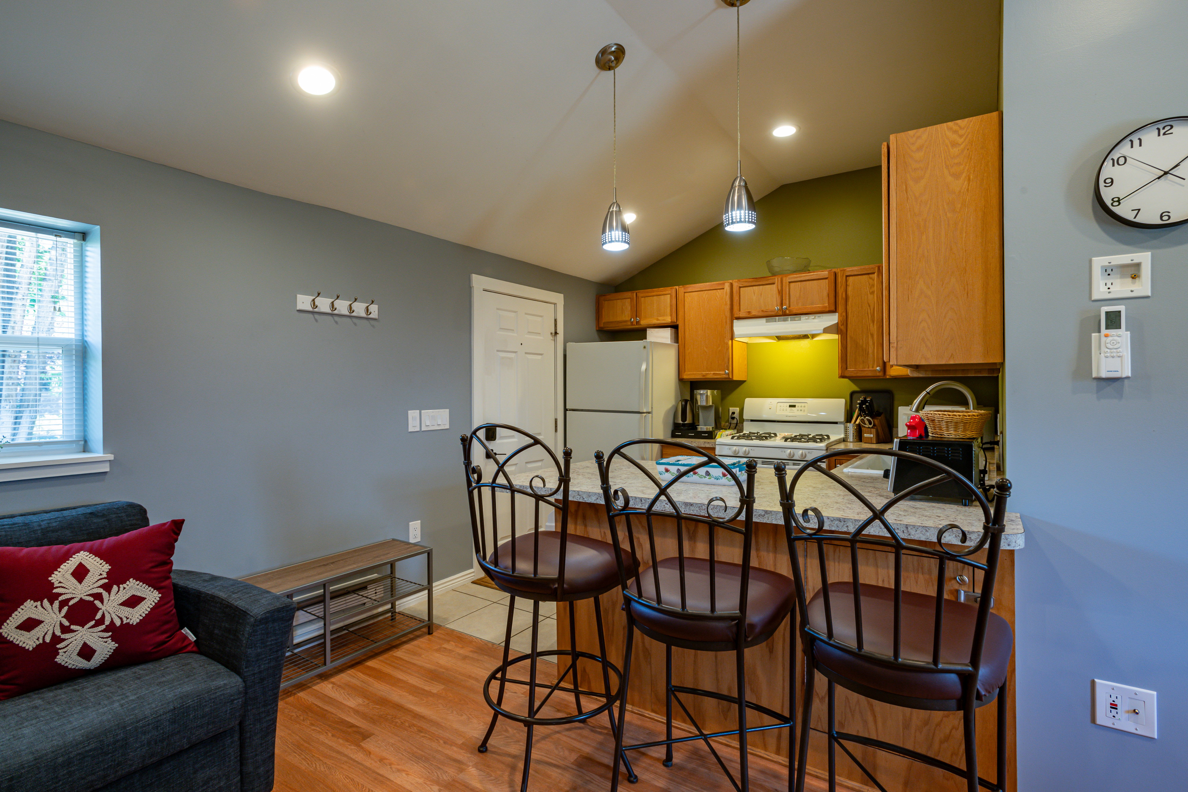 Kitchen featuring a kitchen breakfast bar, white appliances, lofted ceiling, decorative light fixtures, and light wood-style flooring