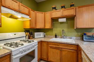 Kitchen with white appliances, light countertops, and wood finish cabinets