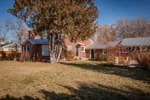 Back of property with brick siding, a yard, and a chimney