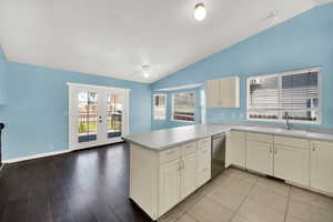 Kitchen featuring french doors, a peninsula, vaulted ceiling, light countertops, and dishwasher