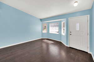 Foyer entrance with baseboards and dark wood-type flooring