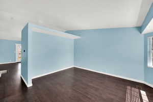 Spare room featuring dark wood finished floors and baseboards