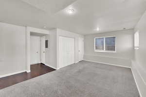 Unfurnished bedroom with a textured ceiling and dark colored carpet