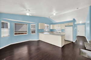 Kitchen featuring white appliances, light countertops, a peninsula, and dark wood-style floors