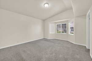 Empty room with carpet and vaulted ceiling