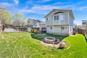 Rear view of house featuring a fire pit, a fenced backyard, and a wooden deck