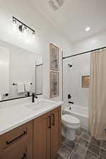 Bathroom with vanity, shower / tub combo with curtain, and dark tile patterned flooring