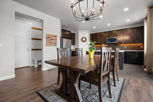 Dining area featuring hanging lights and dark wood-style flooring